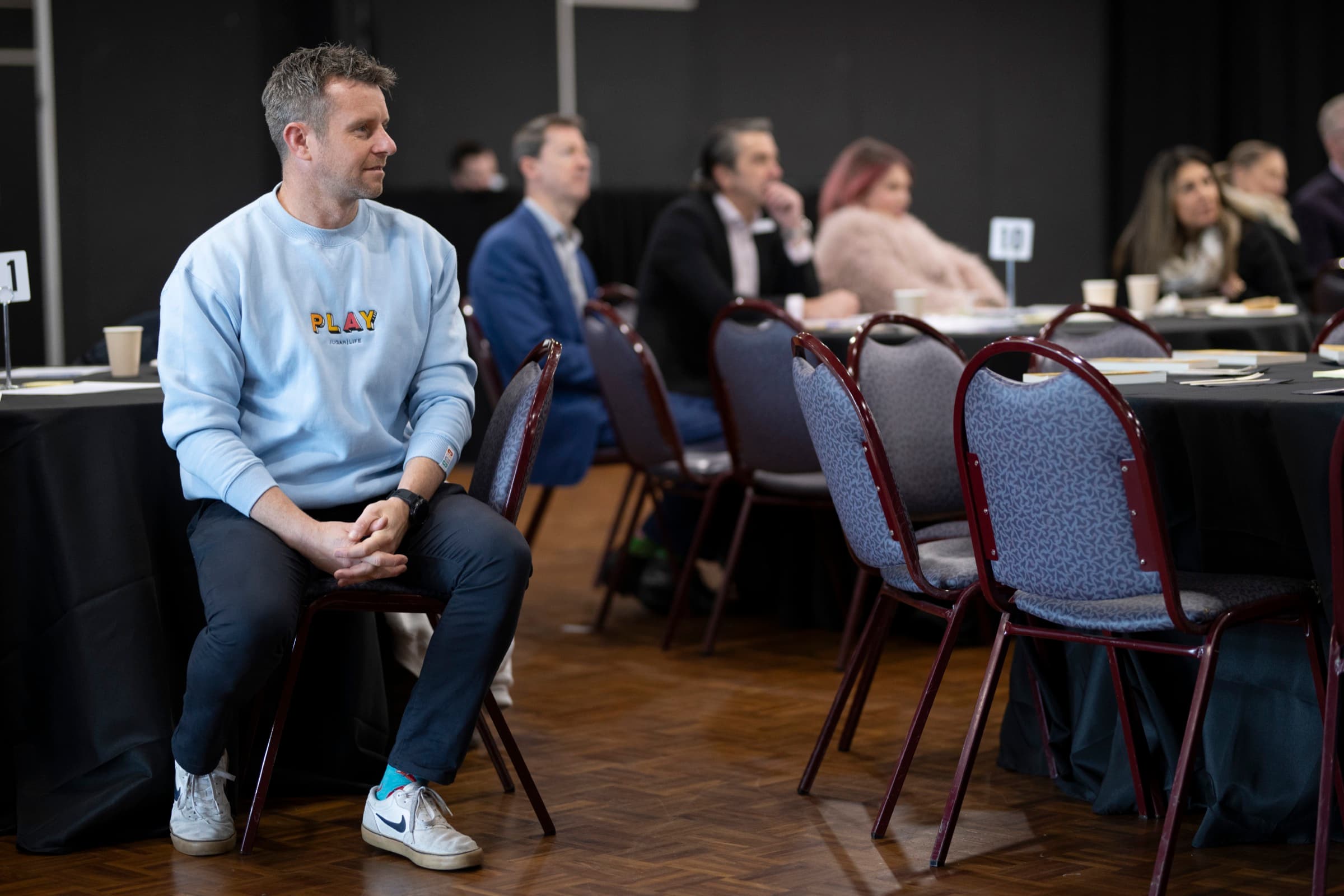 Dale Sidebottom seated at the side of a room, listening to the conversation during a session