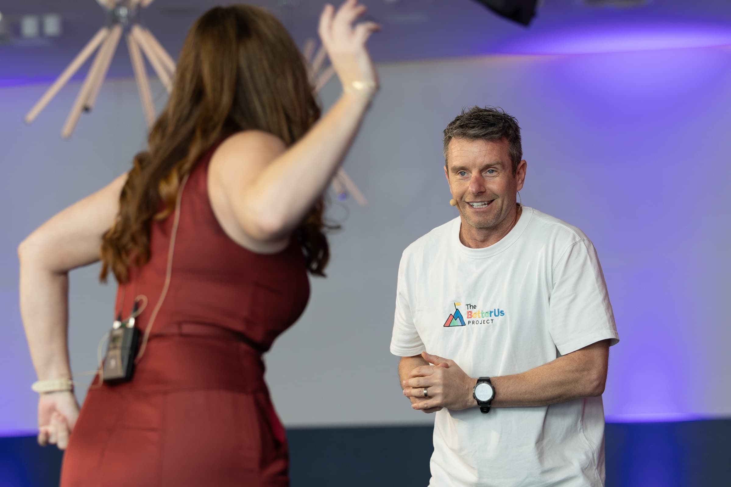 A Better Us Project facilitator smiling as a participant, seen from behind, raises both hands mid-activity